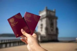 Hand holding two Portuguese passports with Belem Tower in Lisbon in the background